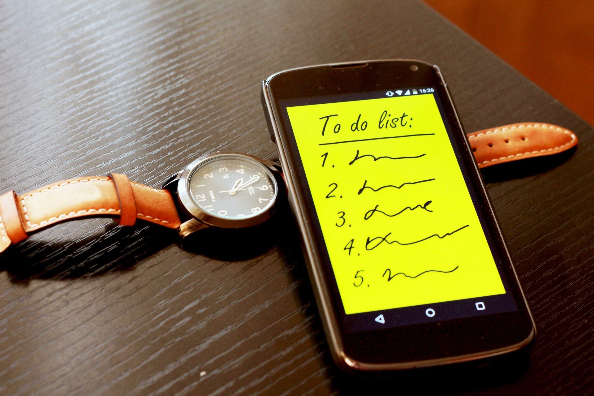 Cellphone with to do list written on it and a watch underneath